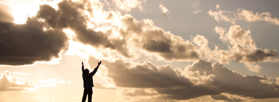 man reaching his hands up to the sky