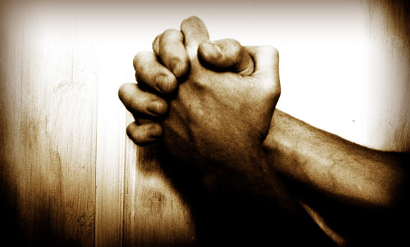 The image show a set of hands intertwined in prayer